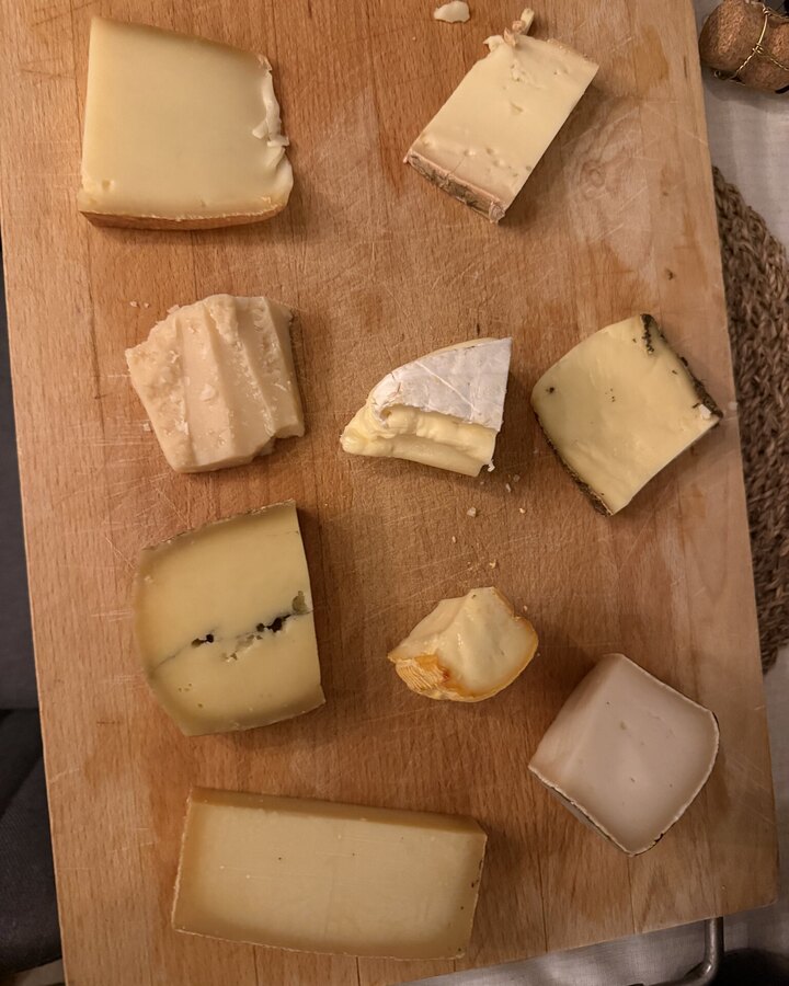 Holzbrett mit neun Stücken französischem Käse: Weichkäse mit Blütenrinde, ein halbfester Käse mit dunkler Ader, ein kleiner Rotschmierkäse und mehrere gereifte Hartkäse
