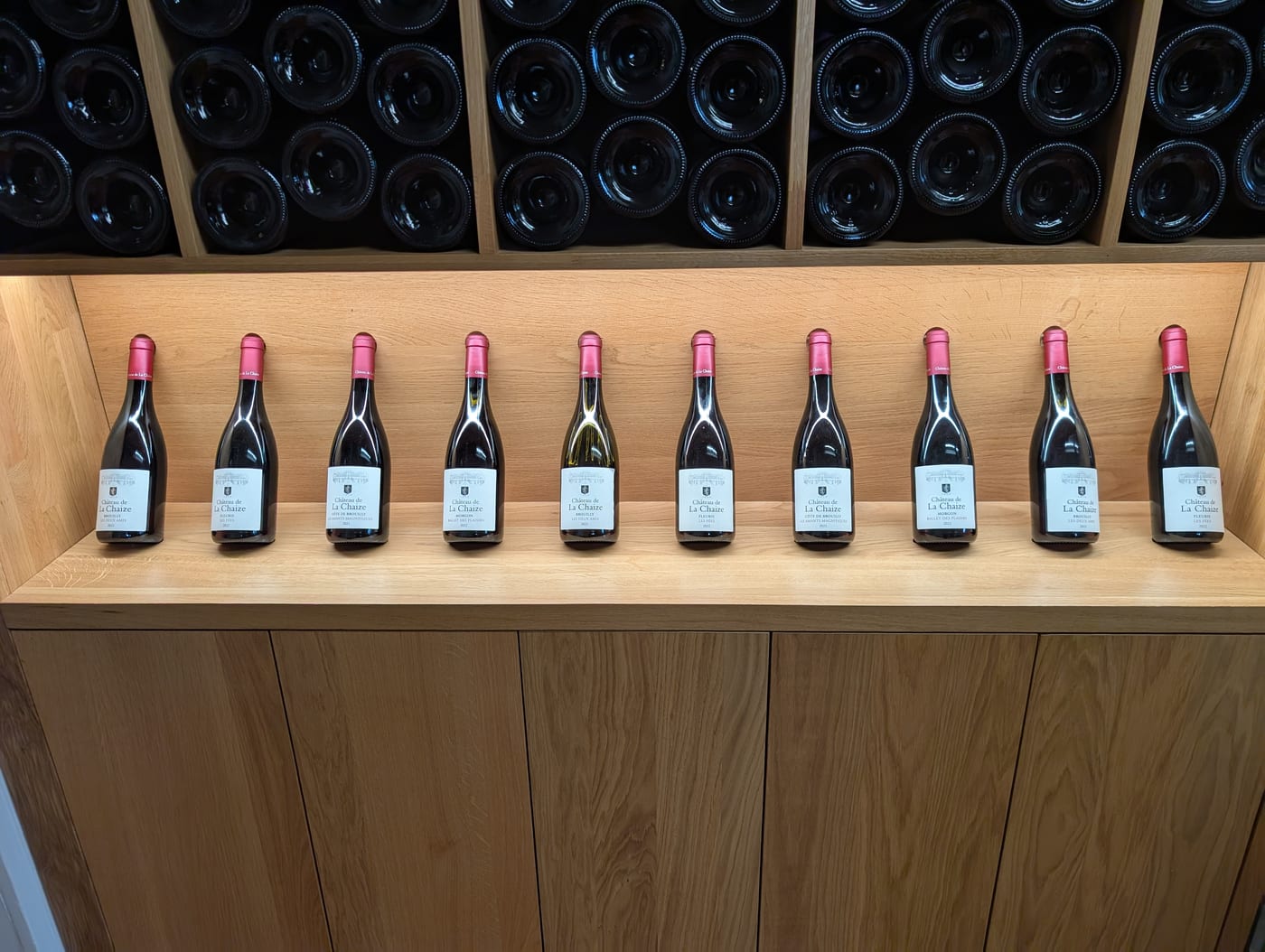 Flaschen von Château de La Chaize in einer Reihe vor einem Weinregal