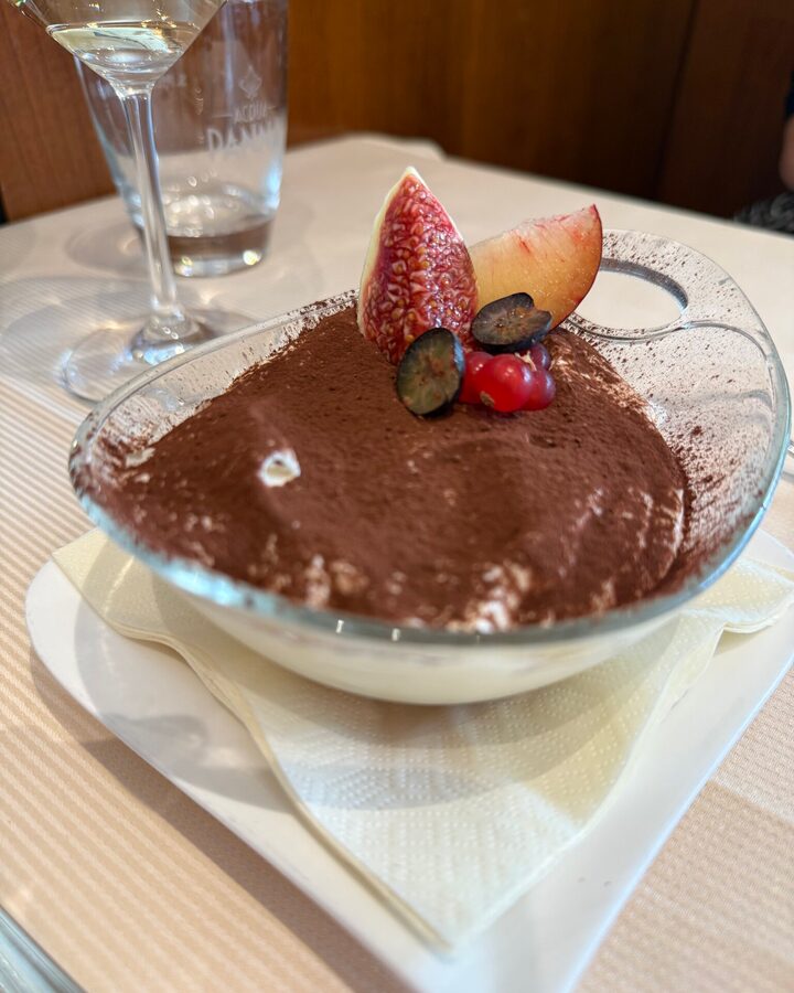 Tiramisu mit dicker Kakaoschicht in einer Glasschale, garniert mit Feige, Pflaume und Beeren
