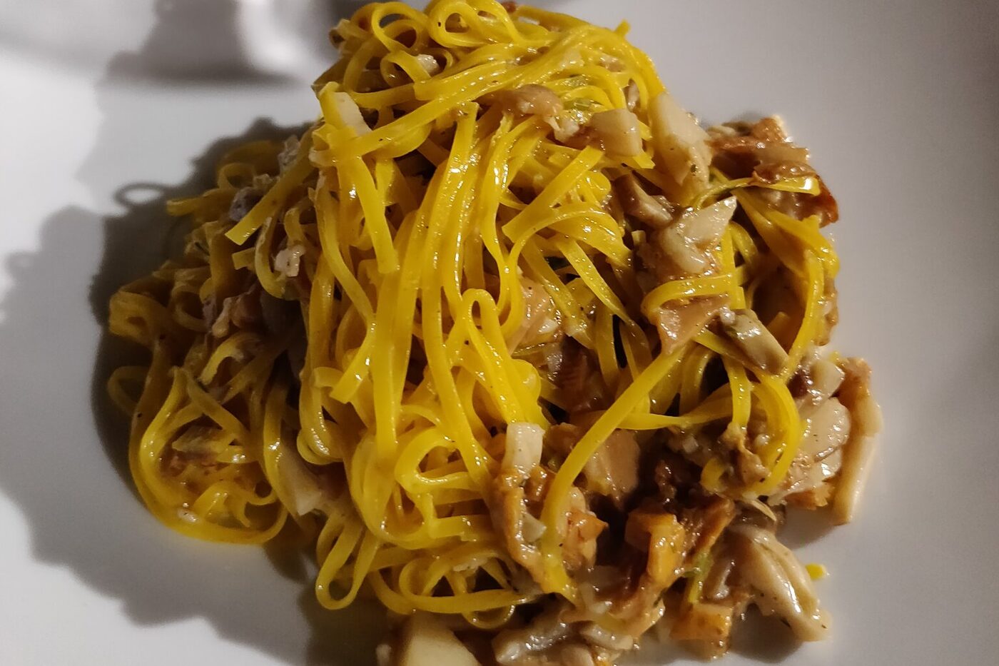 Teller Tajarin-Pasta mit gebratenen Pilzen auf weißem Teller in einem Restaurant